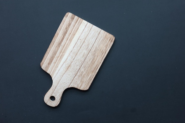 Wooden chopping board on black background top down