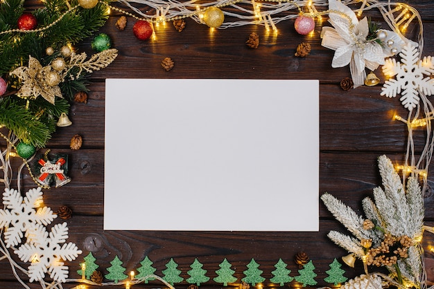 The wooden Christmas background is decorated with festive decor, lanterns, snowflakes and branches of the Christmas tree. Christmas card. Winter holiday season. Happy New Year.