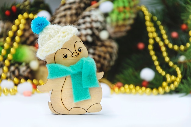 Wooden Christmas toy penguin in a hat on a thematic background