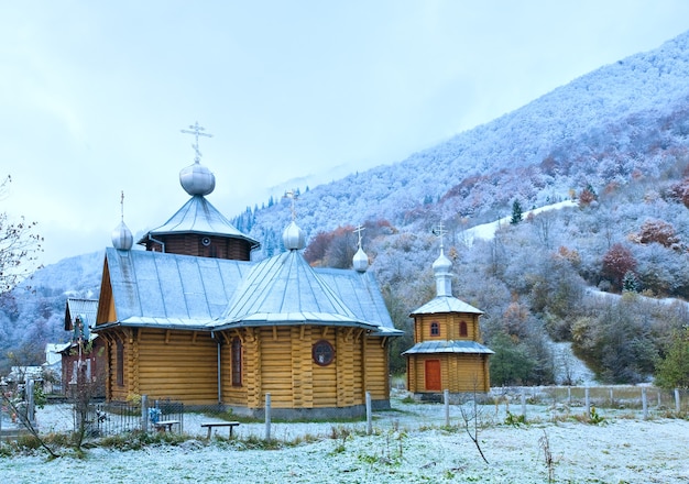 Wooden church and autumn mountain forest with first frost on trees (Carpathian, Ukraine).