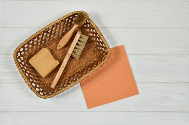 Wooden cleaning brushes and solid natural soap in a basket on a white background Zero alternative for a plastic product Ecofriendly concept