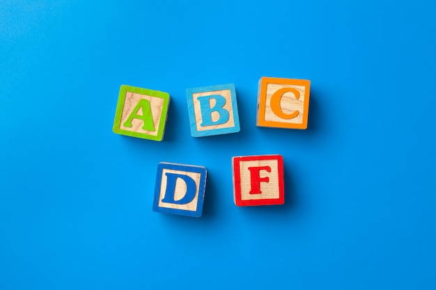 Wooden colorful alphabet blocks on blue background