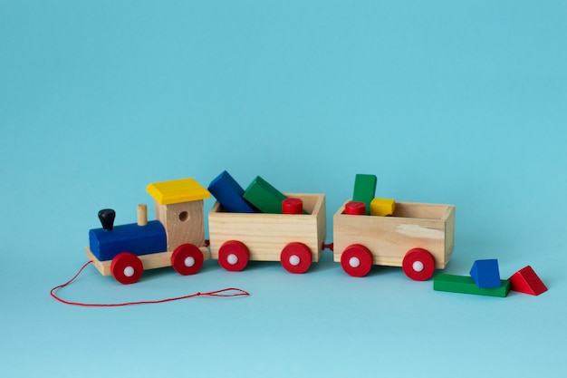 Wooden colorful toy train with details on a soft blue