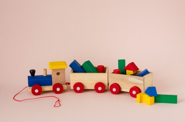 Wooden colorful toy train with details on a soft pink