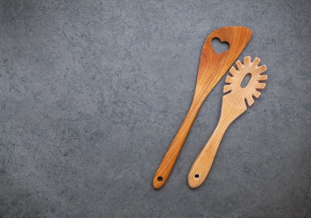 The wooden cooking utensils border on dark stone background.