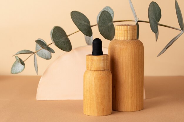 Wooden cosmetics containers on the pastel background.Geometrical podium and fresh eucalyptus branch behind.Earth colors,zero waste containers.Mockup concept.