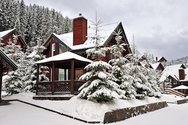 Wooden cottage holiday house in mountain holiday resort covered with fresh snow in winter.