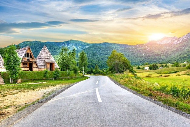 Wooden cotteges near road in mountains of Montenegro at sunset