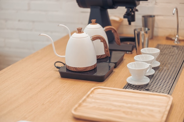 Wooden counter with kettles coffee cups and tray in cafeteria