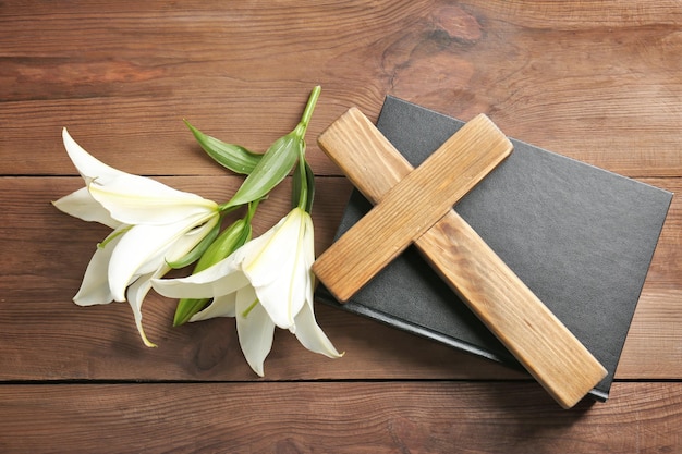 Wooden cross Holy Bible and white lily on table