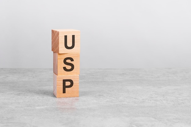 Wooden cube on a concrete surface with text USP copy space on right for design gray background