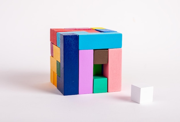 Wooden cube from multicolored blocks with one missing element Construction last step concept Kids game for logical thinking development