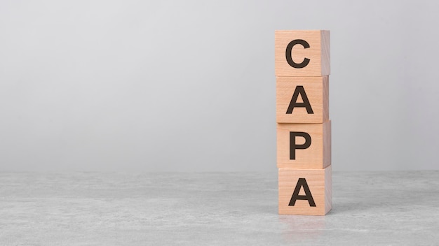 Wooden cube on a white table with text capa concept of business financial investment economy copy space on left for you design gray background