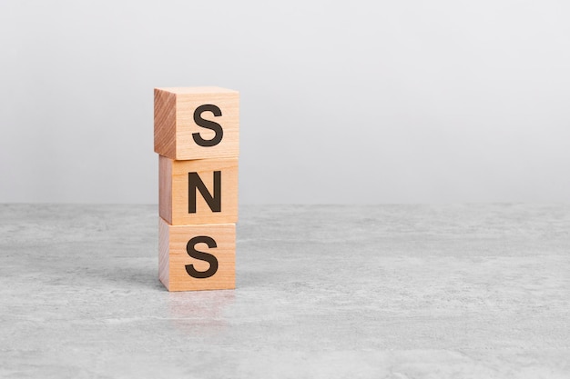 Wooden cube on a white table with text SNS concept of business financial investment economy copy space on right for you design gray background SNS  short for Social Networking Service