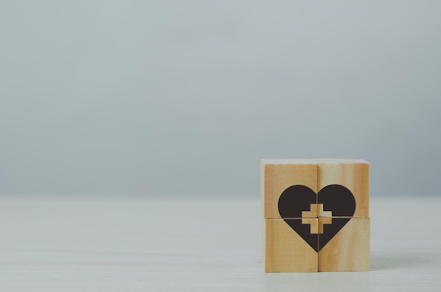 Wooden cube with health insurance icon on table background