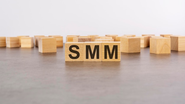 Wooden cube with the letter from the SMM word wooden cubes standing on gray background SMM short for Social Media Marketing