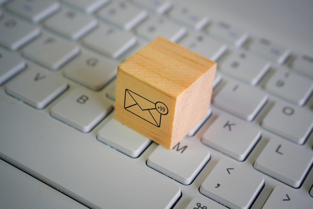 Photo wooden cube with new email notification icon on top of keyboard communication and technology concept