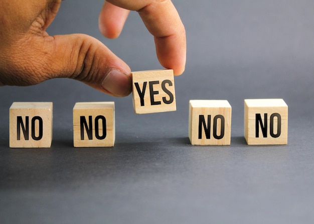 wooden cube with the words yes and no hand choose the word yes the concept of wrong and right