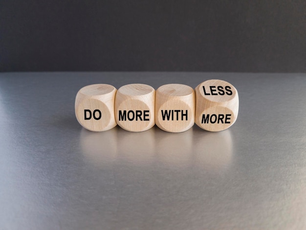 Wooden cubes form the expression 039do more with less039 Beautiful grey table black background