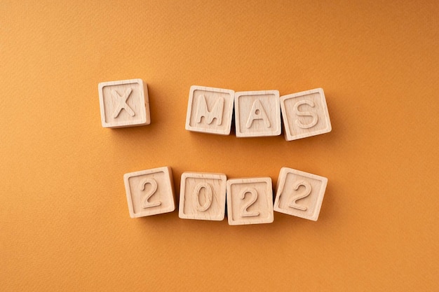 The wooden cubes say Xmas 2022 Wooden cubes with letters and numbers on an orange background New Year's card