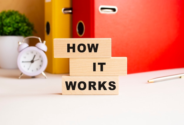 Wooden cubes stacked on top of each other make up the HOW IT WORKS inscription. Design on the desktop.