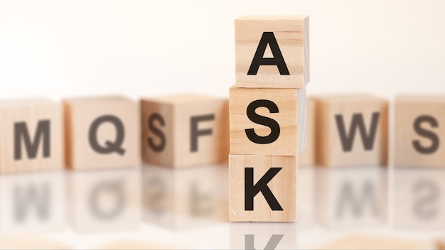 Wooden cubes with letters ASK arranged in a vertical pyramidbusiness concept. ASK short for bid ask