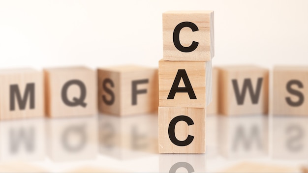 Wooden cubes with letters cac arranged in a vertical pyramid, on the light background, reflection surface, business concept. cac short for customer acquisition cost