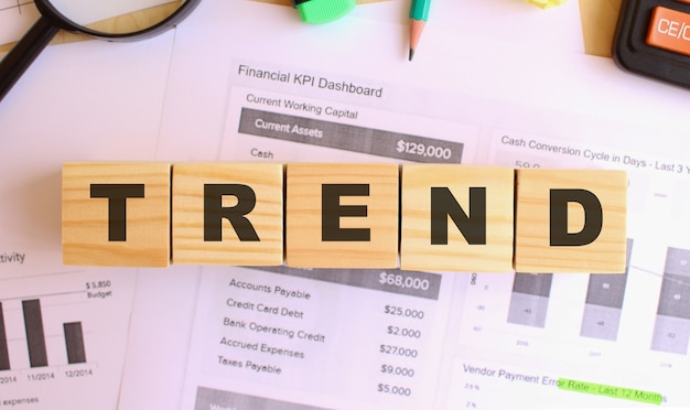 Wooden cubes with letters on the table in the office. Text TREND. Financial concept.