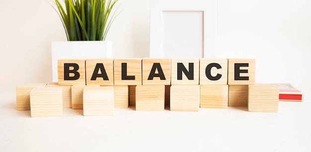 Wooden cubes with letters on a white table. The word is BALANCE.