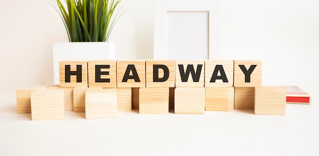 Wooden cubes with letters on a white table The word is HEADWAY White background