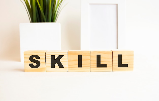 Photo wooden cubes with letters on a white table. the word is skill. white background with photo frame, house plant.