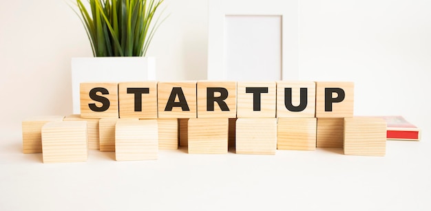 Wooden cubes with letters on a white table the word is startup white background