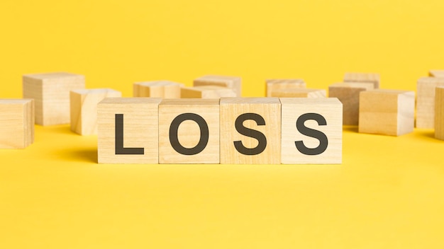 Wooden cubes with LOSS word on yellow background financial loss business concept