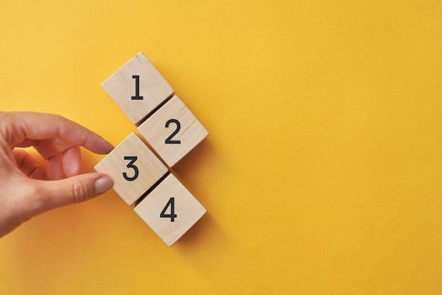 Wooden cubes with numbers from one to four, priority selection on a yellow background