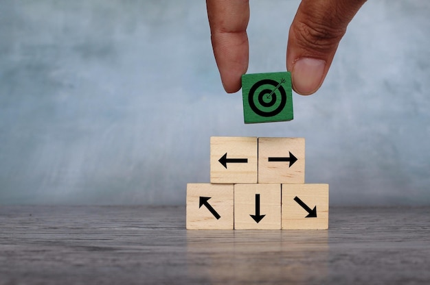 Wooden cubes with target icon and arrow pointing different direction Organize a team set a goal