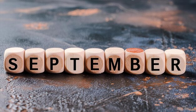 Wooden cubes with text SEPTEMBER on dark cement background Month of year Autumn season