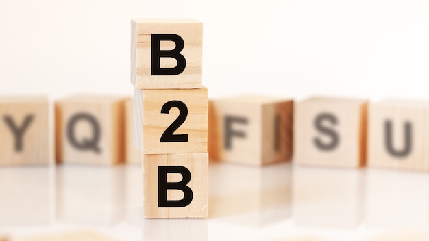 Wooden cubes with word B2B arranged in a vertical pyramid, on the white background is a row of wooden cubes with letters, business concept. B2B - short for business to business