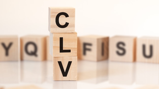 Wooden cubes with word CLV arranged in a vertical pyramid, on the white background is a row of wooden cubes with letters, reflection from the surface of the table, business concept