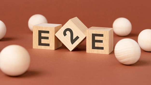 Wooden cubes with word e2e on brown background front view