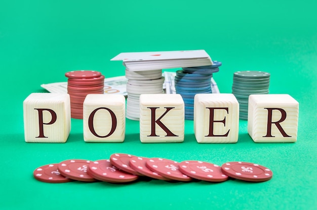 Wooden cubes with word POKER poker chips deck of playing cards and money on a green background