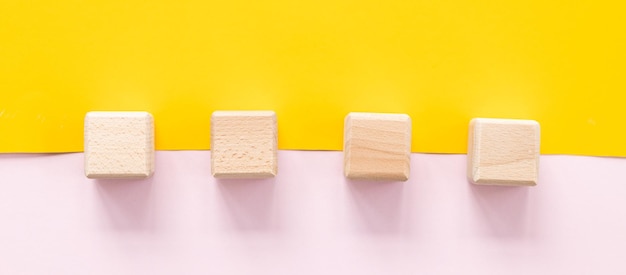 Wooden cubes on yellowpink background