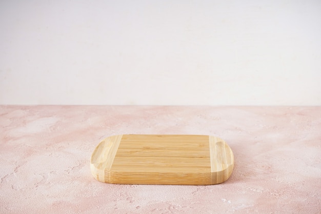 Wooden cutting board on a beige background with place for text.