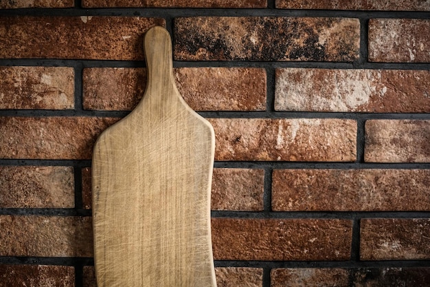 Wooden cutting board at the kitchen against bricks wall