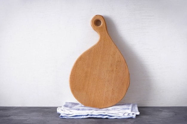 Wooden cutting board and kitchen towel on a gray background, place for text.