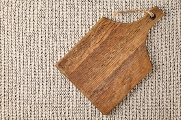 Wooden cutting board on a knitted beige sweater background