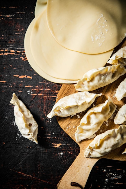 Photo a wooden cutting board with dumplings and a stack of cheese.