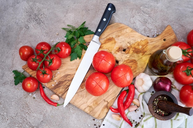 Wooden cutting board with knife and tomatoes on grey kitchen concrete or stone table