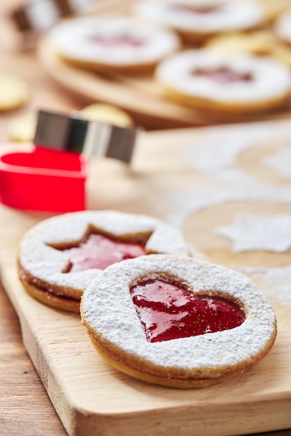 Wooden cutting board with powdered sugar and linzer cookies baking decoration process