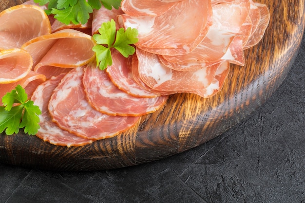 Wooden cutting Board with prosciutto, bacon, salami and sausages on a wooden background. meat platter