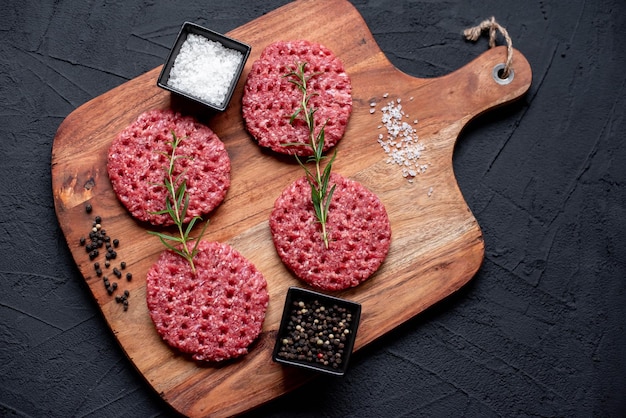 A wooden cutting board with raw meats on it.